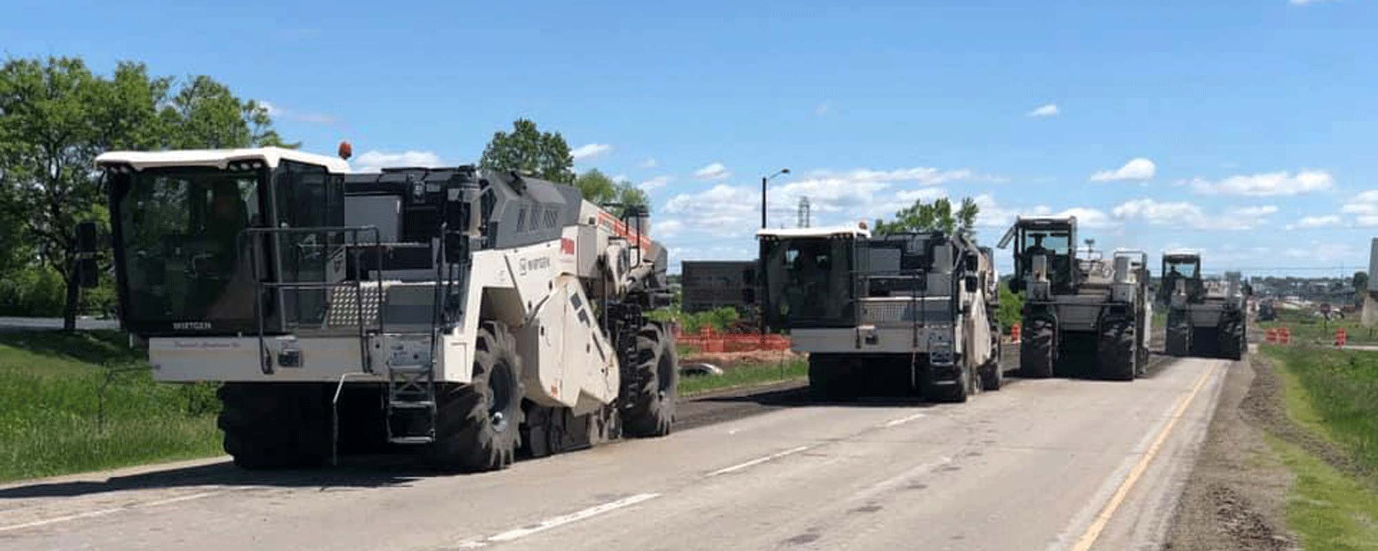 A fleet of milling and pulverizing equipment working on a road